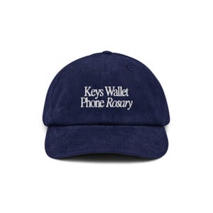 May include: A navy blue corduroy baseball cap with white embroidery that reads "Keys Wallet Phone Rosary".