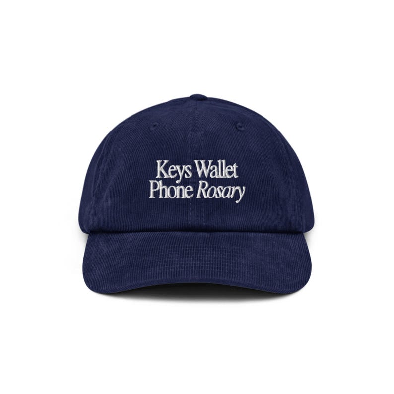May include: A navy blue corduroy baseball cap with white embroidery that reads "Keys Wallet Phone Rosary".