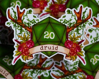 May include: A green 20-sided die with the number 20 on it, surrounded by antlers, flowers, and greenery. The die has the word "druid" written on a banner below it.