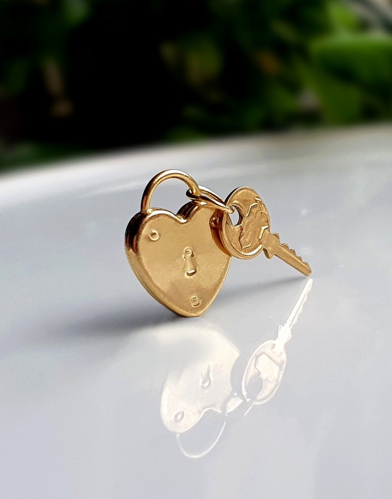 May include: A gold heart-shaped padlock with a key attached. The padlock has a keyhole and the key has a decorative design.