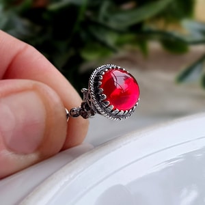 Puede incluir: Un solo pendiente de piedra roja con engaste de plata. El pendiente tiene un diseño detallado y adornado.