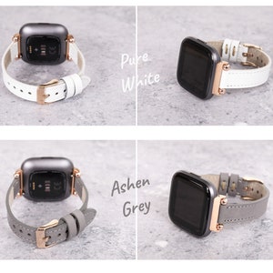 Op de afbeelding: Twee horlogebandjes voor een smartwatch. Het bandje links is van lichtgrijs leer met ros&eacute;gouden hardware. Het bandje rechts is van wit leer met ros&eacute;gouden hardware. De tekst "Ashen Grey" staat onder het linker bandje en de tekst "Pure White" staat onder het rechter bandje.