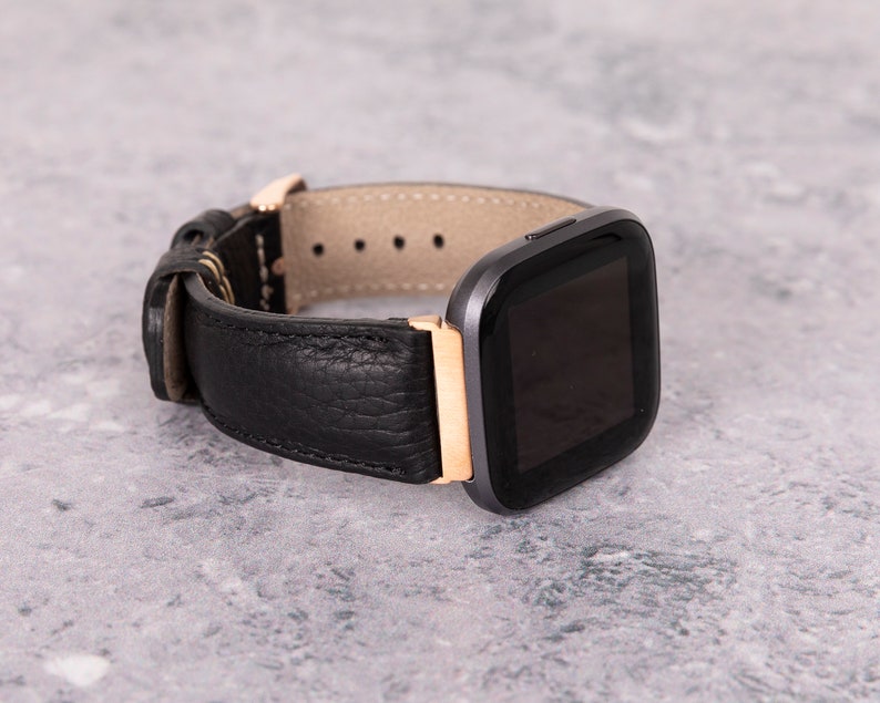 May include: A black leather watch band with a rose gold accent and a black smartwatch face.