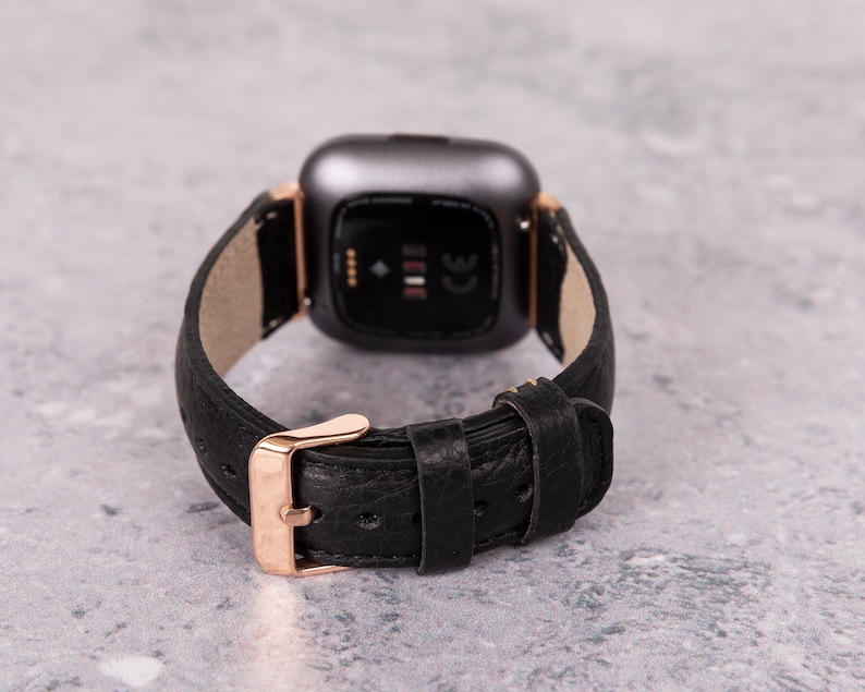 May include: A black leather watch band with a rose gold buckle and a silver smartwatch face.