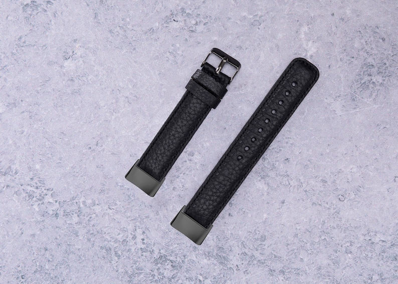 May include: Two black leather watch bands with silver buckles. The bands are on a gray textured surface.