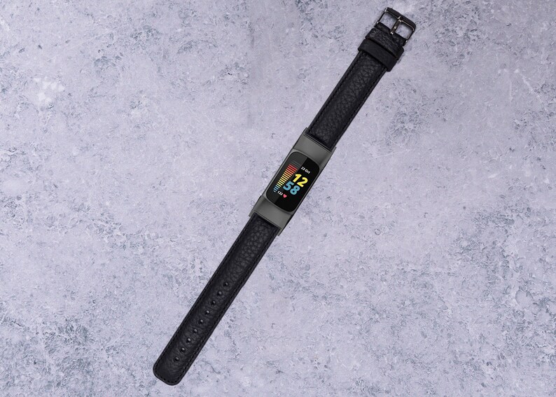 May include: A black fitness tracker with a black leather band. The screen displays the time, 12:58, and a heart rate graph.