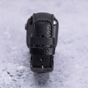 May include: A black leather watch band with a silver buckle.