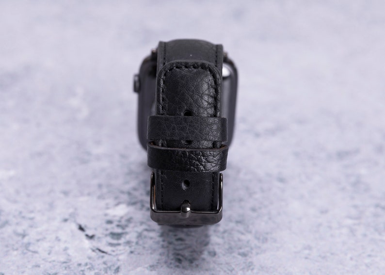 May include: A black leather watch band with a silver buckle.