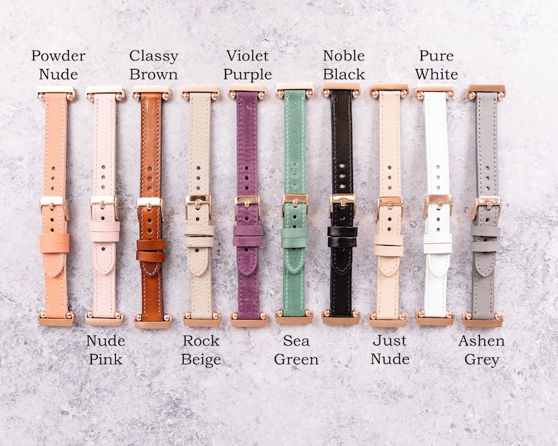Op de afbeelding: Tien verschillende gekleurde lederen horlogebandjes met ros&eacute;gouden hardware. De bandjes zijn gelabeld met namen zoals "Powder Nude", "Classy Brown", "Violet Purple", "Noble Black", "Pure White", "Nude Pink", "Rock Beige", "Sea Green", "Just Nude" en "Ashen Grey".