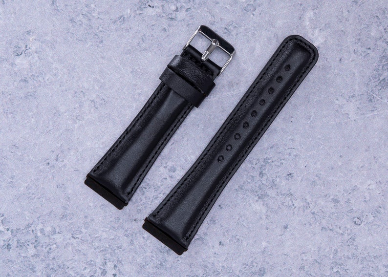 May include: Two black leather watch straps with silver buckles. One strap has a smooth finish, while the other has a row of small holes.