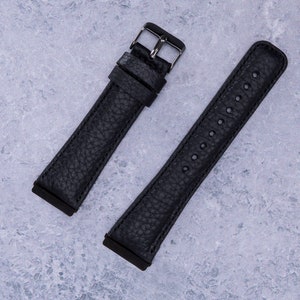 May include: Two black leather watch straps with silver buckles. One strap has a smooth finish and the other has a textured finish.