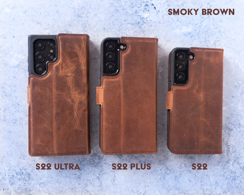 May include: Three leather phone cases in the colour "Smoky Brown" for the Samsung Galaxy S22 Ultra, S22 Plus, and S22. The cases are all closed and have a flap that covers the screen.