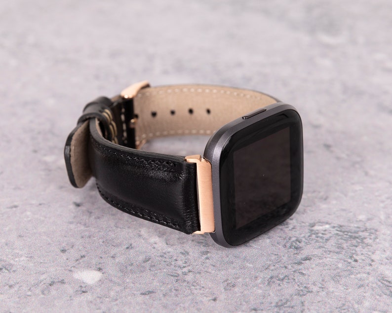 May include: A black leather watch band with a rose gold buckle and a black smartwatch face.