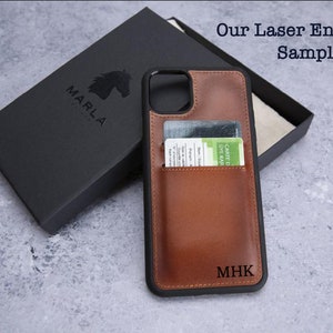 May include: A brown leather phone case with a card slot and a black border. The case has the initials "MHK" engraved on the back. The case is shown next to a black box with the word "MARLA" printed on it.
