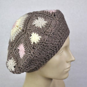 Puede incluir: Un gorro de punto marrón con un patrón floral blanco y rosa.