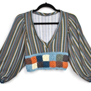 May include: A blue and brown striped cropped top with a crocheted trim. The trim is made of squares in various colours, including orange, blue, green, and brown.