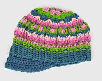 May include: A crocheted hat with a colorful pattern of pink, green, and blue. The hat has a wide brim and is made with a thick yarn.