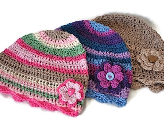 May include: Three crocheted hats with colorful stripes and flower embellishments. The hats are made with different colors of yarn, including pink, green, blue, purple, and brown.
