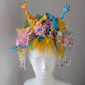 Gosande giraffer, blommor och rosetter, roligt, ljust festivalhuvudbonad/krona med fjädrar, slöja, pompoms och Swarovskikristaller