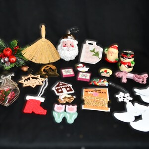 Peut inclure: Assortiment d'ornements et de décorations de Noël comprenant un Père Noël, un bonhomme de neige, un balai, une maison en pain d'épices, une décoration en forme de cœur, une décoration en forme d'étoile, une décoration en bois, une couronne, une chaussette, un paquet, une cloche, un flocon de neige, une fleur et une bobine de galon métallique.