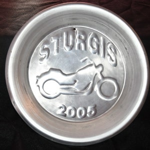 May include: A silver metal plate with a motorcycle silhouette and the text "Sturgis 2005".
