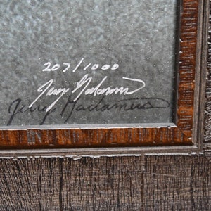 May include: A framed print with a gray background and a handwritten signature that reads "Jerry Madam", along with the number "207/1000".