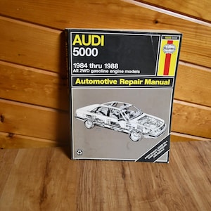 May include: An Audi 5000 automotive repair manual from 1984 to 1988. The cover is black with yellow and red accents and features a diagram of a car. The text on the cover reads "Automotive Repair Manual."