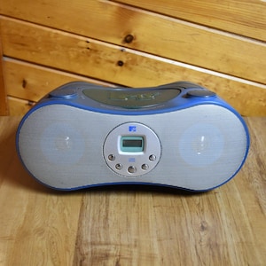 May include: A blue and silver CD player with a digital display and two speakers. The player has a CD slot on the top and buttons on the front.