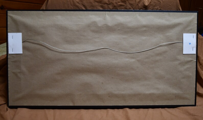 May include: The back of a framed picture with a brown paper backing and a wire hanger attached. The frame is black.