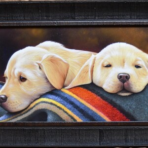 May include: Painting of two yellow Labrador Retriever puppies sleeping on a colorful striped blanket. The puppies are curled up together, with one resting its head on the other's back. The painting is signed by the artist, "Jayne Pederson", and dated "2021/2022".