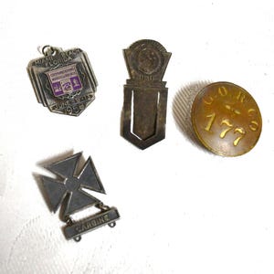 May include: A collection of vintage metal items, including a Miami Beach Florida souvenir, a bookmark, a round brass button with the text "G.O.R. Co. 177", and a "Carbine" badge. The items are arranged on a white surface.