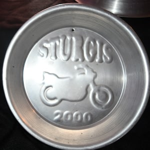 Könnte beinhalten: Ein silberner Metallteller mit den Worten "Sturgis 2000" und einem Motorrad-Design.