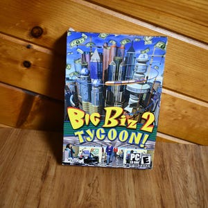 May include: A Big Biz 2 Tycoon! PC CD-ROM game box. The cover shows a cityscape with skyscrapers, money, and the game's title in yellow and green. The bottom of the box shows people in an office setting.