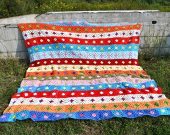 May include: A colorful striped crochet blanket with a diamond pattern. The blanket is made with a variety of colors, including red, orange, yellow, green, blue, and purple.