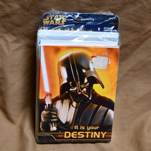 Peut inclure: Un paquet de 8 invitations de fête Star Wars représentant Dark Vador tenant un sabre laser rouge. Les invitations ont un fond jaune, orange et rouge avec le texte "It is your DESTINY".