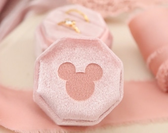 May include: A pink velvet ring box with a Mickey Mouse silhouette on the lid.