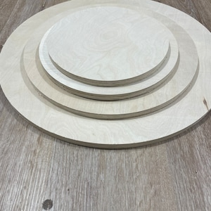 May include: Three unfinished wooden circles of varying sizes, stacked on top of each other. The circles are made of light-coloured wood and have a smooth surface.