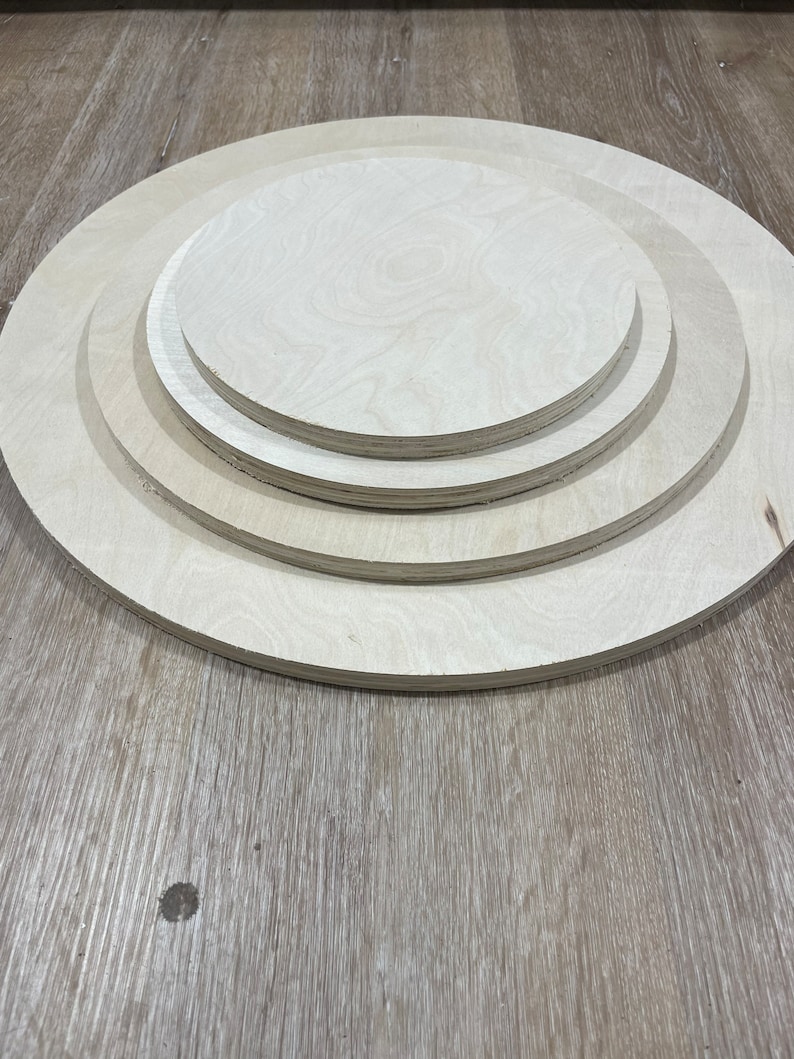 May include: Three unfinished wooden circles of varying sizes, stacked on top of each other. The circles are made of light-colored wood and have a smooth surface.