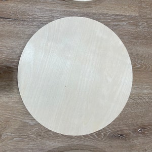 May include: A plain, round, wooden disc with a light beige color and a smooth surface.