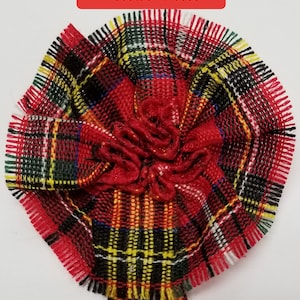 Peut inclure: Un ruban en tartan rouge, noir, jaune et vert noué en une mini-fleur écossaise. Le ruban est étiqueté "Stewart Red Tartan Ribbon as Mini Scottish Blossom".