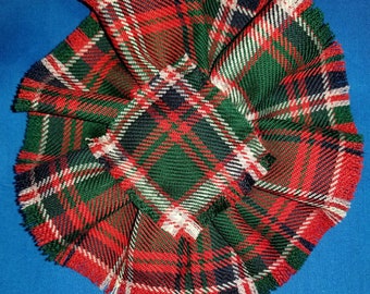May include: A red, green, white, and black plaid fabric rosette with frayed edges.