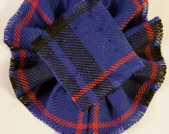 Può includere: Uno spillo per kilt in tartan blu, rosso e nero con bordo a frangia. Lo spillo è etichettato "Morgan, Blu, Moderno".