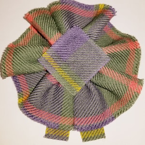 Puede incluir: Un lazo de tela a cuadros verde, morado, rosa y amarillo con un centro cuadrado.