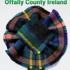 May include: A green, blue, yellow, and pink tartan fabric bow with fringed edges. The bow is tied with two long tails. The text "Offally County Ireland" is visible above the bow.