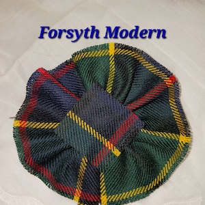 Op de afbeelding: Een strik van groene, gele, rode en blauwe ruitstof met de tekst "Forsyth Modern" erboven.