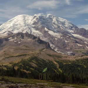 May include: A snow-capped mountain peak with a rocky, green foreground. The mountain is covered in snow and ice, with a few patches of bare rock visible. The foreground is covered in green grass and trees, with a few patches of bare rock visible.