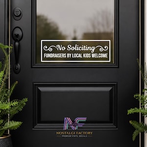 Könnte beinhalten: Eine schwarze Eingangstür mit einem weißen Vinyl-Aufkleber mit der Aufschrift "No Soliciting Fundraisers by Local Kids Welcome". Der Aufkleber ist rechteckig mit dekorativen Verzierungen. Die Tür hat einen schwarzen Griff und eine kleine Pflanze links.