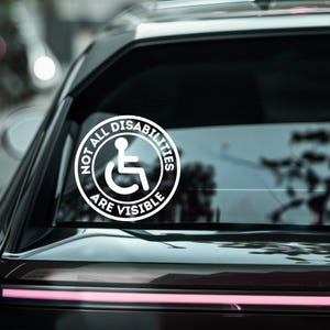 以下が含まれることがあります： 車のリヤウィンドウに貼られた、車椅子マークと「NOT ALL DISABILITIES ARE VISIBLE」の文字が入った白いビニールステッカー。見えない障害への意識を高めるためのものです。