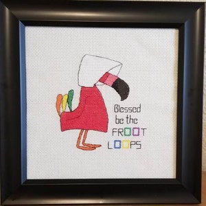 Puede incluir: Una bordado de punto de cruz de un flamenco rosa con un gorro blanco y sosteniendo un cartel que dice "Blessed be the Froot Loops".