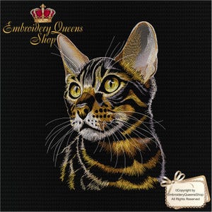 Peut inclure: Portrait brodé d'un chat tigré noir et or. Le chat a de grands yeux jaunes et de longues moustaches. L'image comprend le texte "Embroidery Queens Shop" et une couronne.